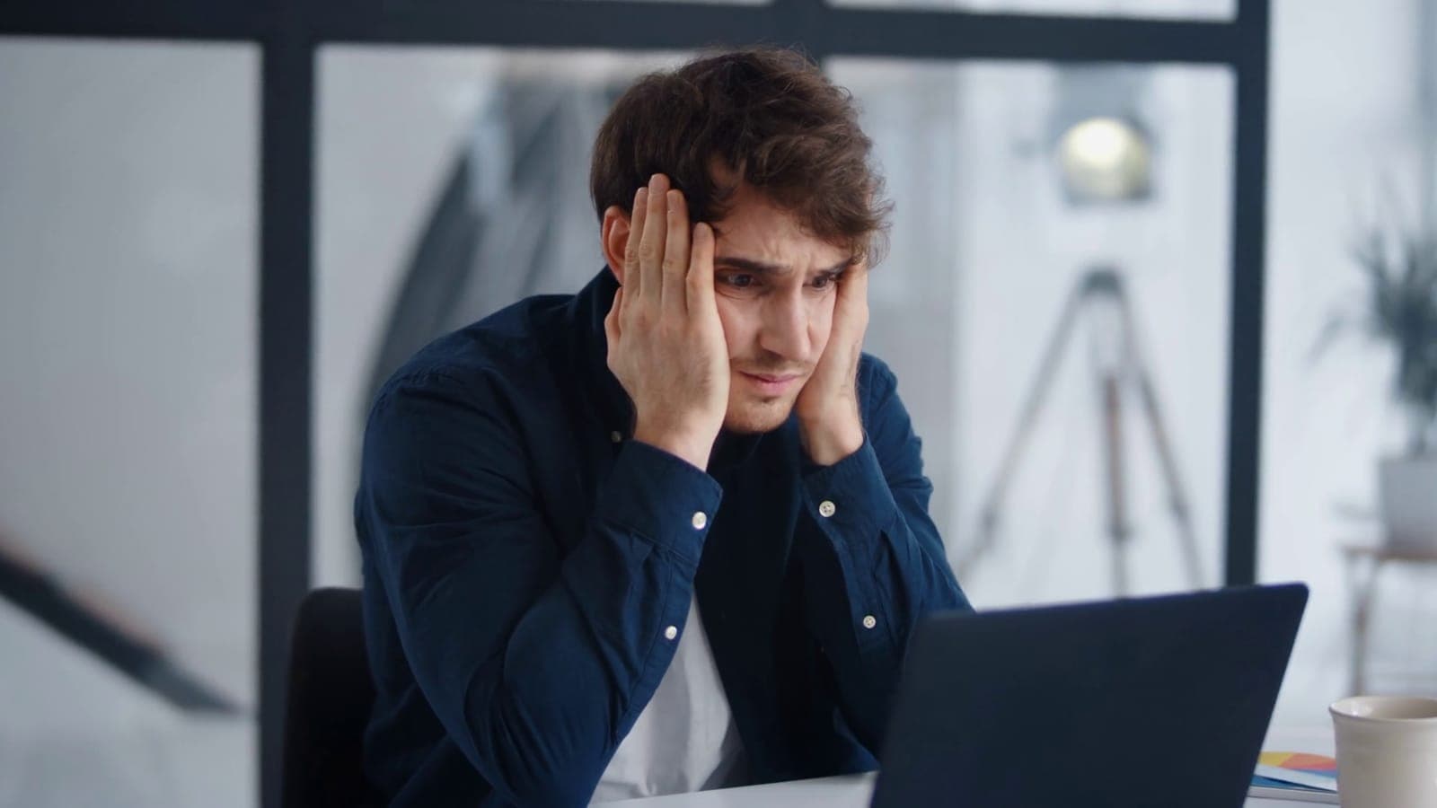 Frustrated employee at a laptop after a phishing email