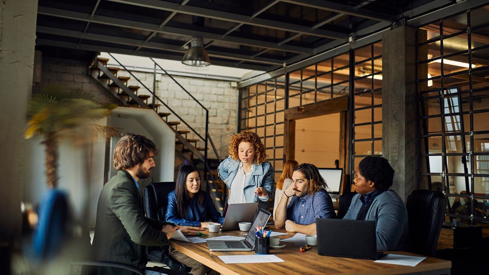 Diverse IT team collaborating around laptops in a modern open-plan office