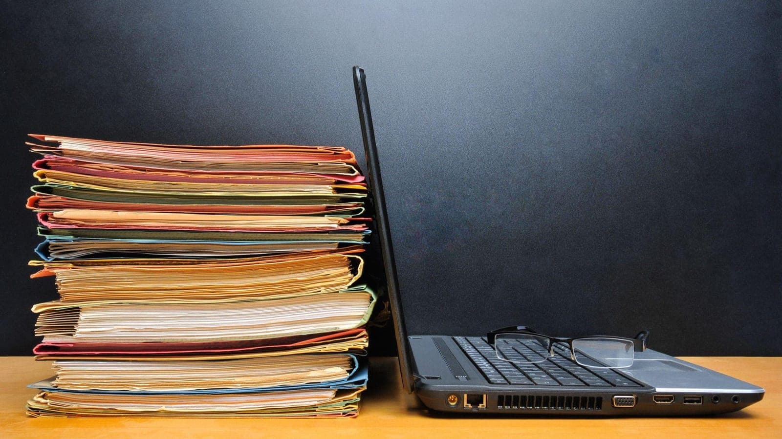 Stack of documents beside a laptop, representing service paperwork
