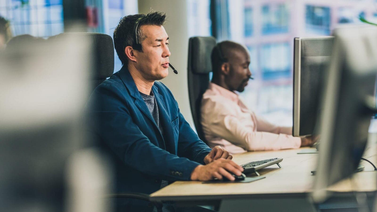 Support agent with a headset helping a customer at a service desk