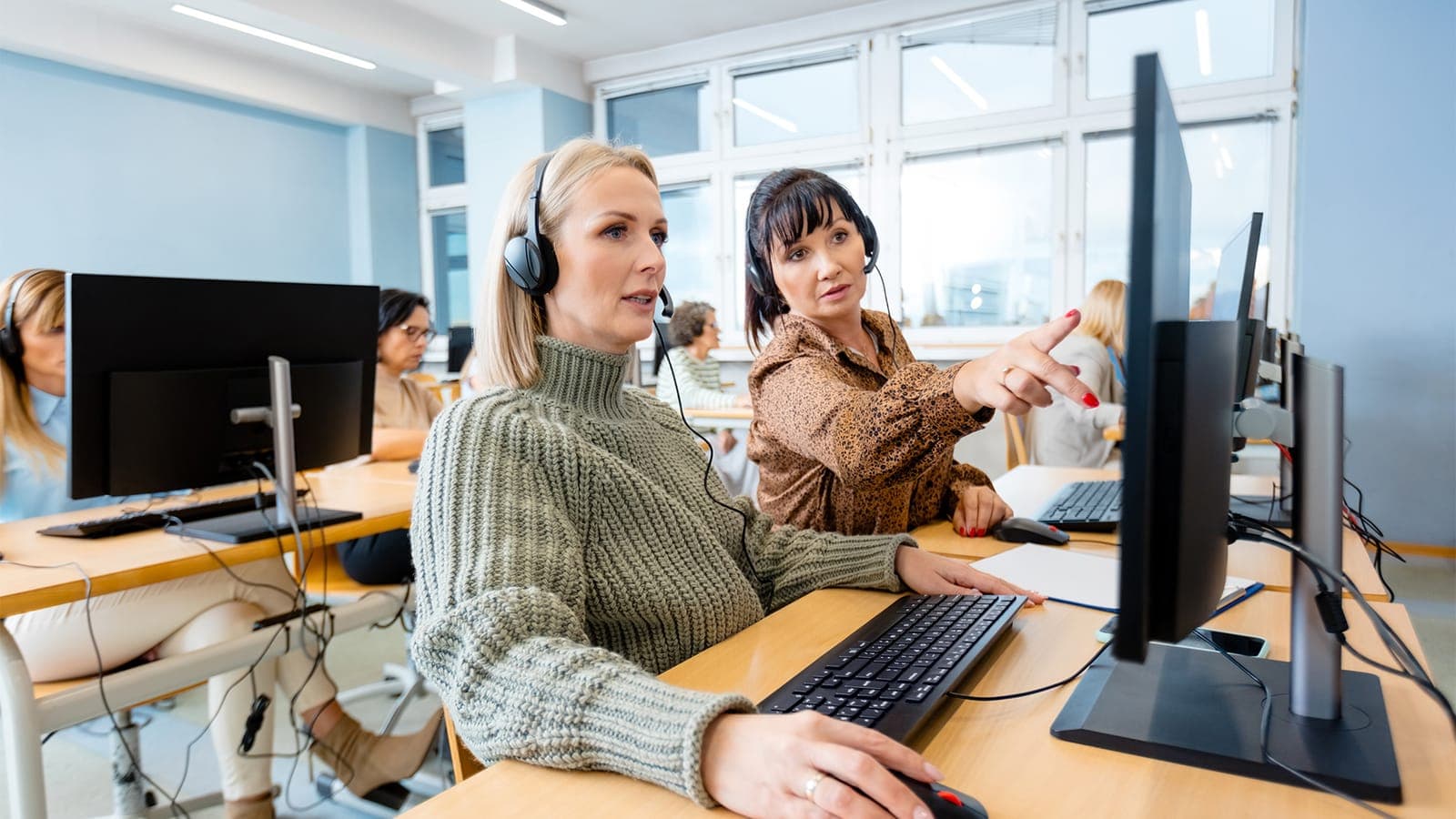 Support agents wearing headsets assisting clients at an IT helpdesk